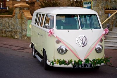 Gorgeous white VW wedding campervan decorated with pink ribbons and floral garland. 