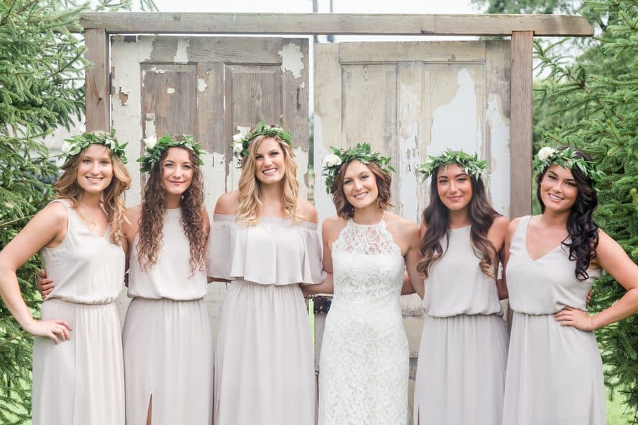 Bride and bridesmaids in pastel color dresses and crowns made of foliage.