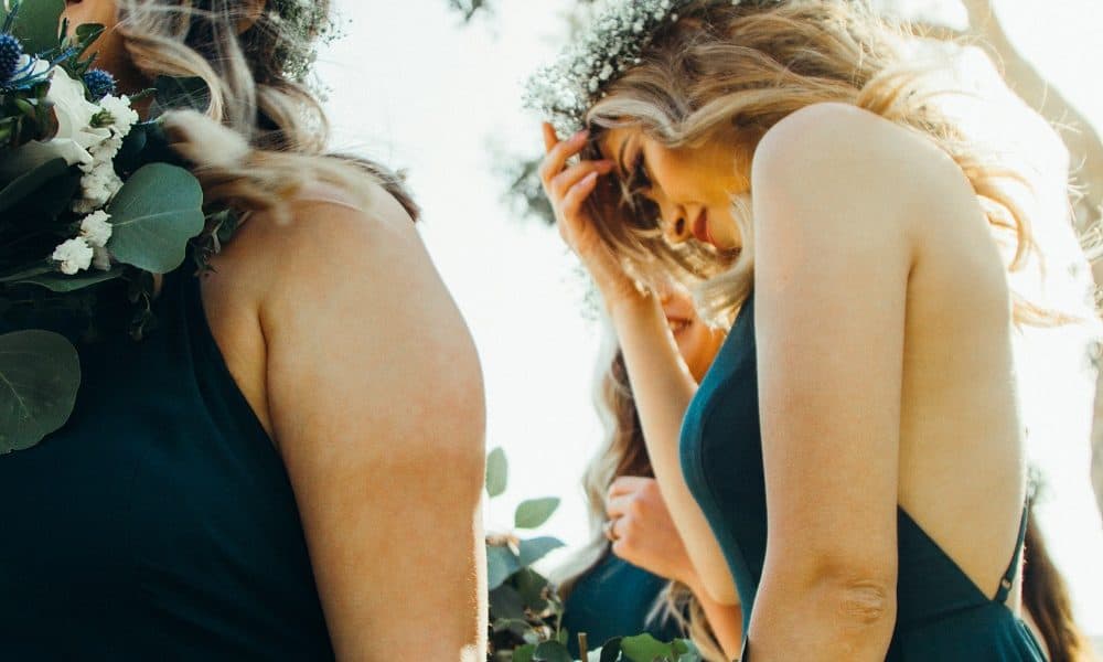 Two bridesmaid dressed in dark green dresses and floral crowns.