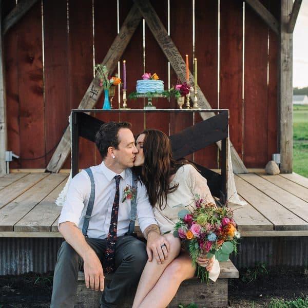 Couple sitting kissing in a barn.