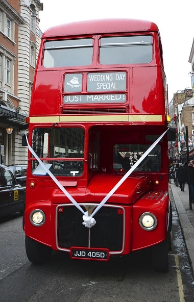 Red London wedding bus, decorated with white ribbons.