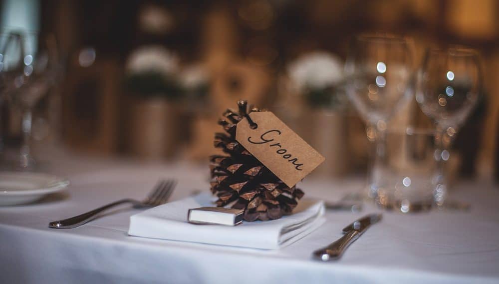 Pinecone wedding table decoration with brown groom tag.