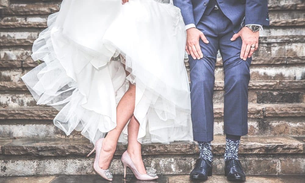 A recently married couple show off their footwear under their wedding clothes.