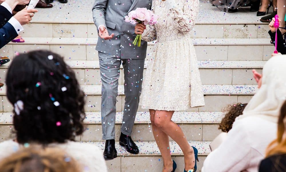 Recently married couple have confetti thrown on them.