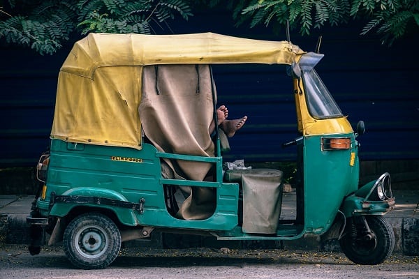 Tuk tuk with a turquoise body and yellow roof.