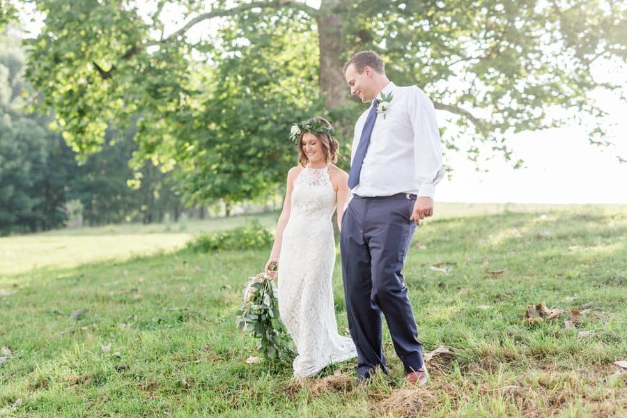 Newly weds walk together with a beautiful tree in the background.