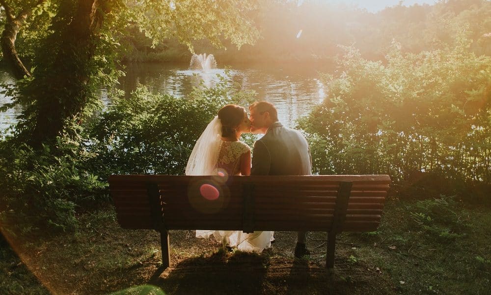 Married couple kissing on a bench during sunset.