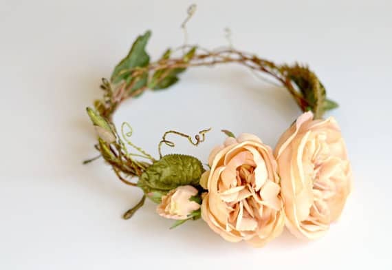 Wooden wreath with peach roses and foliage at the centre.